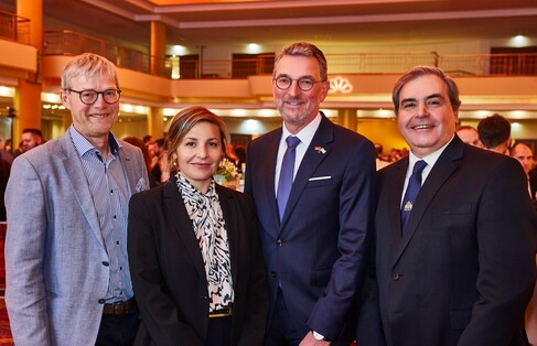 Eine Gruppe von vier Menschen steht im Festsaal des Grand Elysée Hamburg. Es gibt eine Frau und drei Männer, alle sind in eleganter Abendkleidung gekleidet.