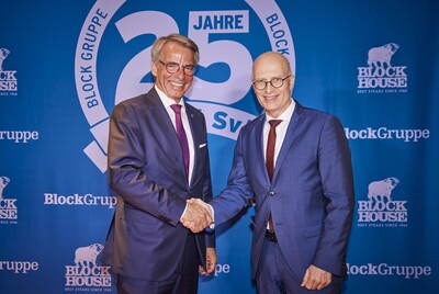 Zwei Männer im Anzug beim Händeschütteln vor Block-Gruppe-Logo.