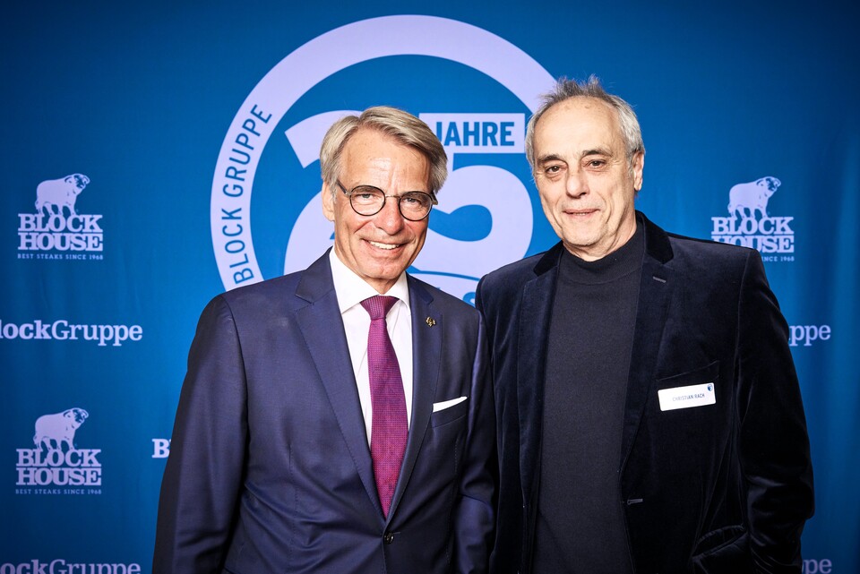 Zwei Männer im Anzug stehen vor einer blauen Fotowand mit dem Logo der Block Gruppe.
