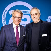 Zwei Männer im Anzug stehen vor einer blauen Fotowand mit dem Logo der Block Gruppe.