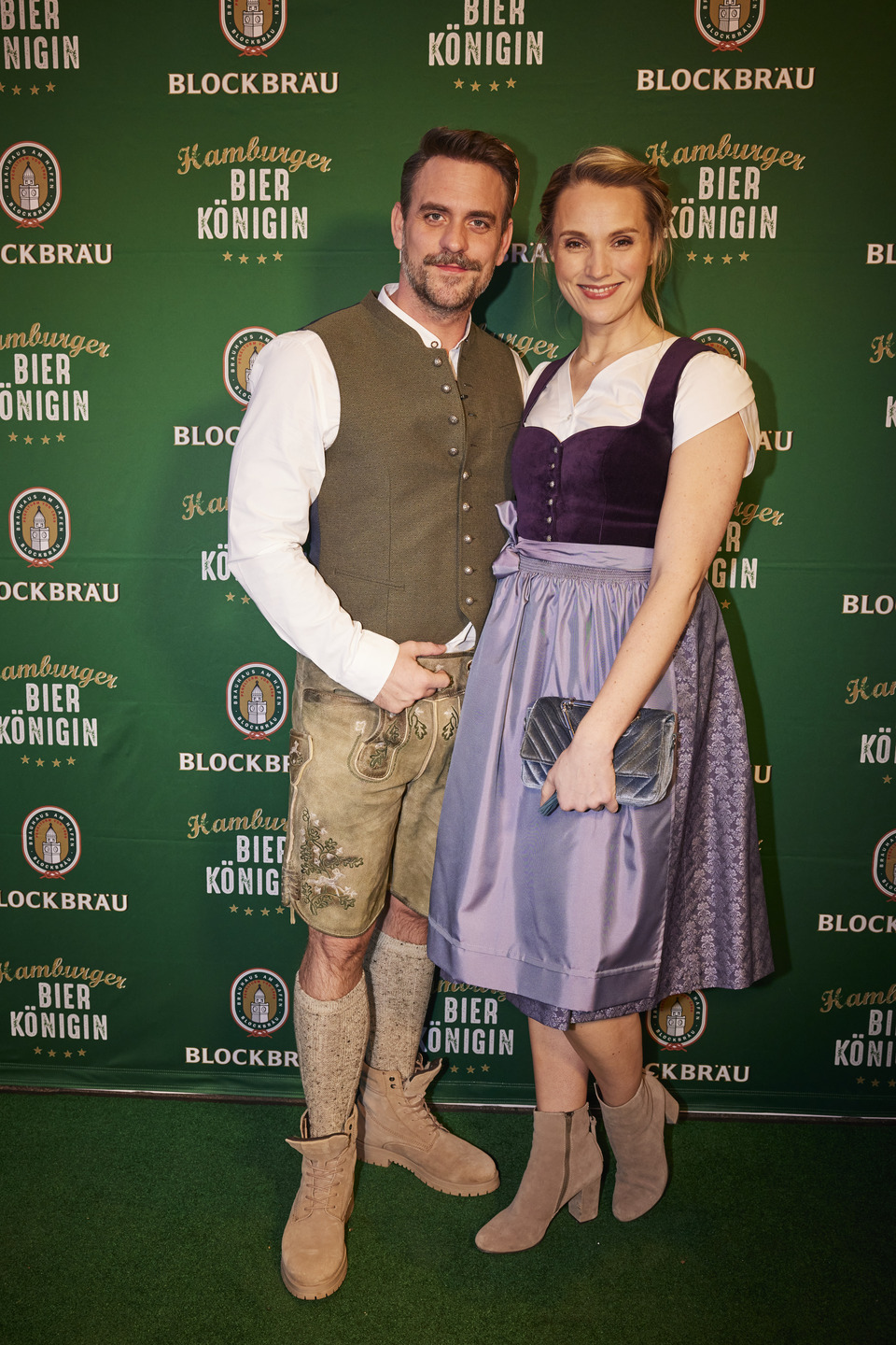 Ein Mann und eine Frau in Trachtenkleidung stehen vor einer Logowand des BLOCKBRÄU