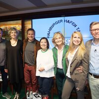 Teilnehmer des 14. Hamburger Hafen Talks (v.l. Herma Koehn, René Steinke, Anna Schäfer, Doris Kunstmann, Thorsten Laussch, Alexandra Rotmann und Helmut Zierl) auf der Bühne nebeneinander stehend und lächelnd.