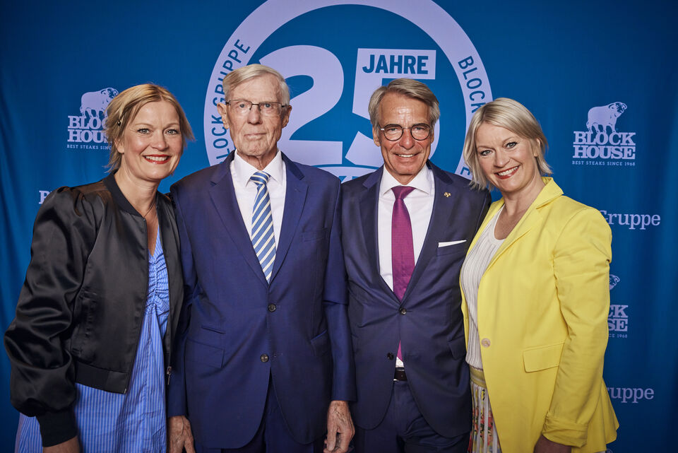Vier Personen posieren vor einem blauen Hintergrund mit dem Logo der Block Gruppe.
